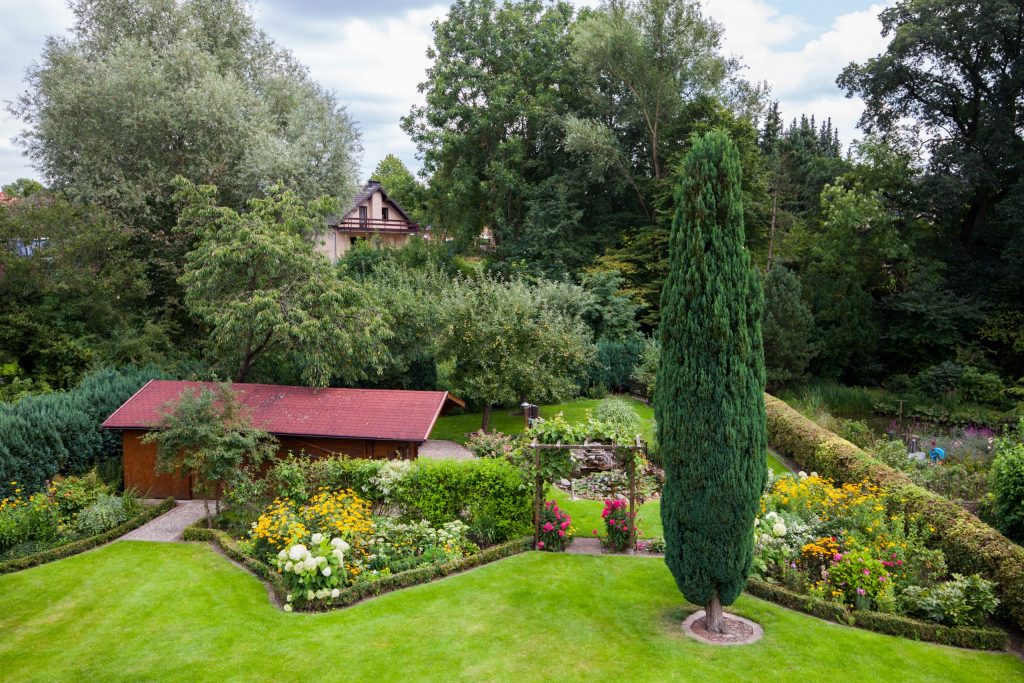 Blick von oben auf den Garten mit Gartenhütte, Beeten und Rasen
