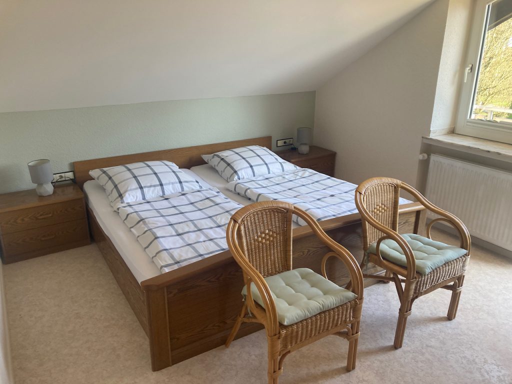 Schlafzimmer mit Doppelbett und zwei Korbstühlen