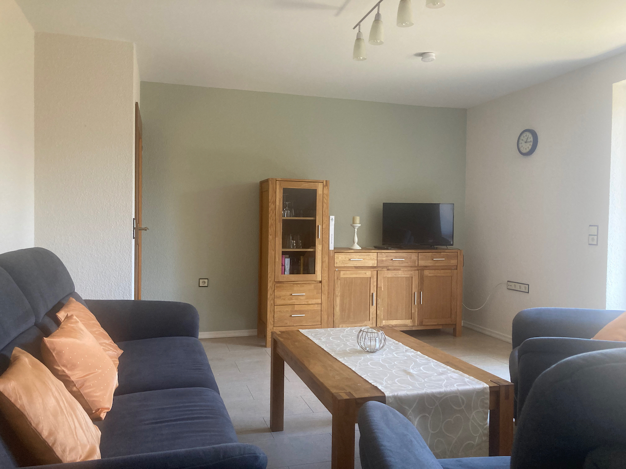 Wohnzimmer mit Sofa, Sessel, Couchtisch und Fernseher