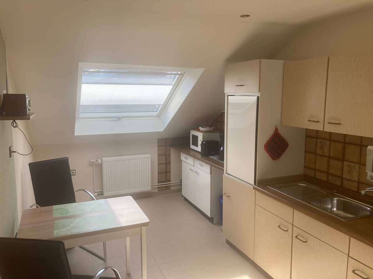 Küche mit Esstisch, Kühlschrank und Dachfenster